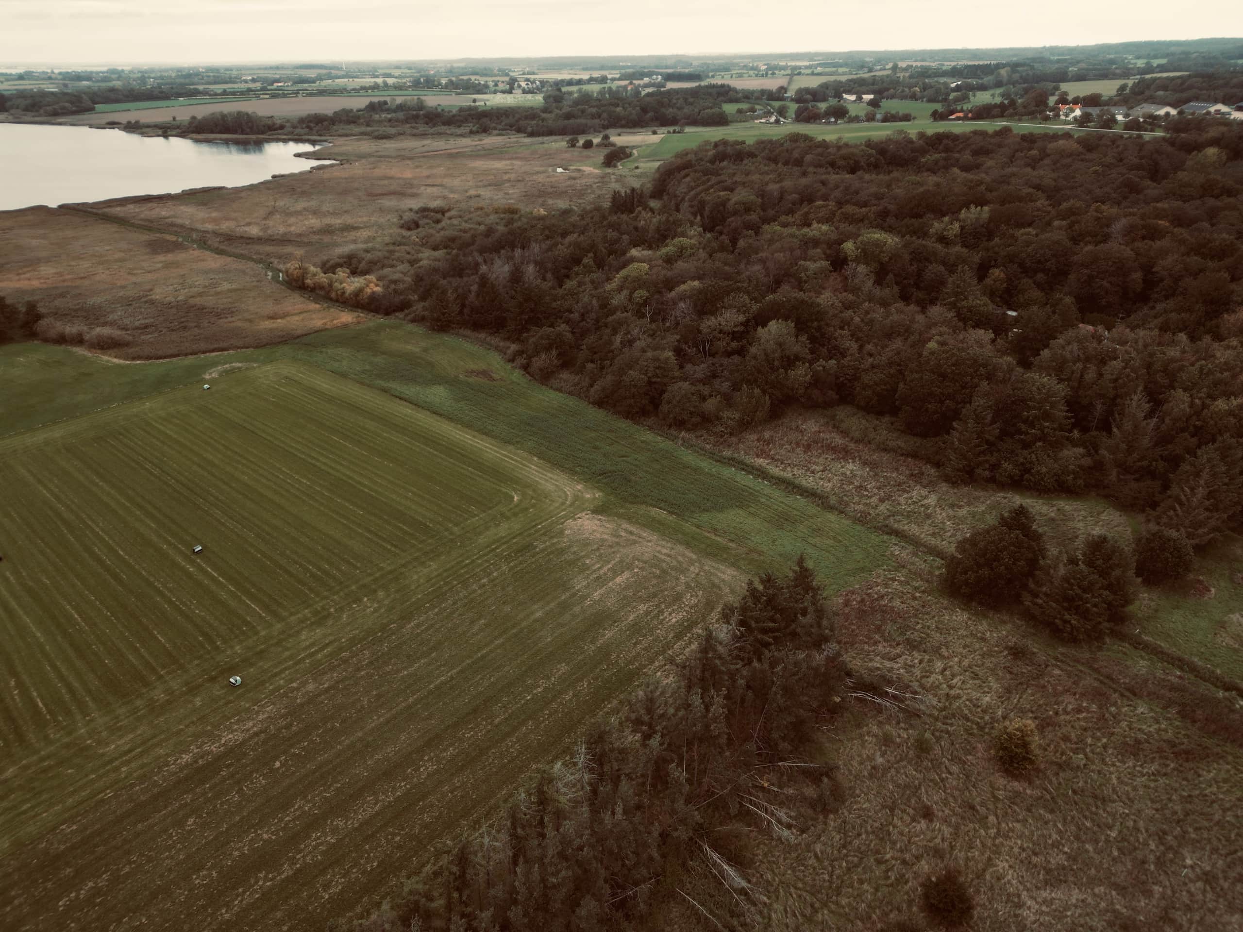 Luftfoto af Sandager Plads og landskabet omkring med marker, skov og vand.